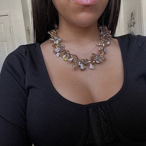 Woman wearing a statement floral necklace and black top.